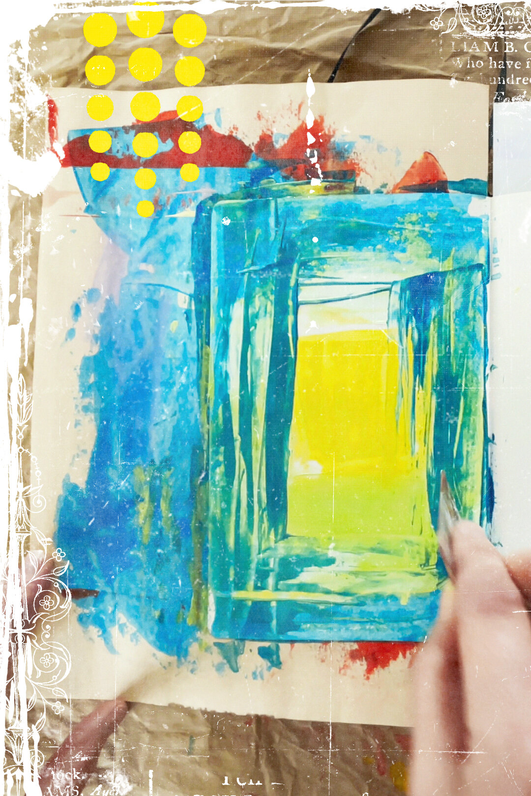 A visual journal page being created with a yellow background, as a hand scrapes blue paint across it with a plastic card.